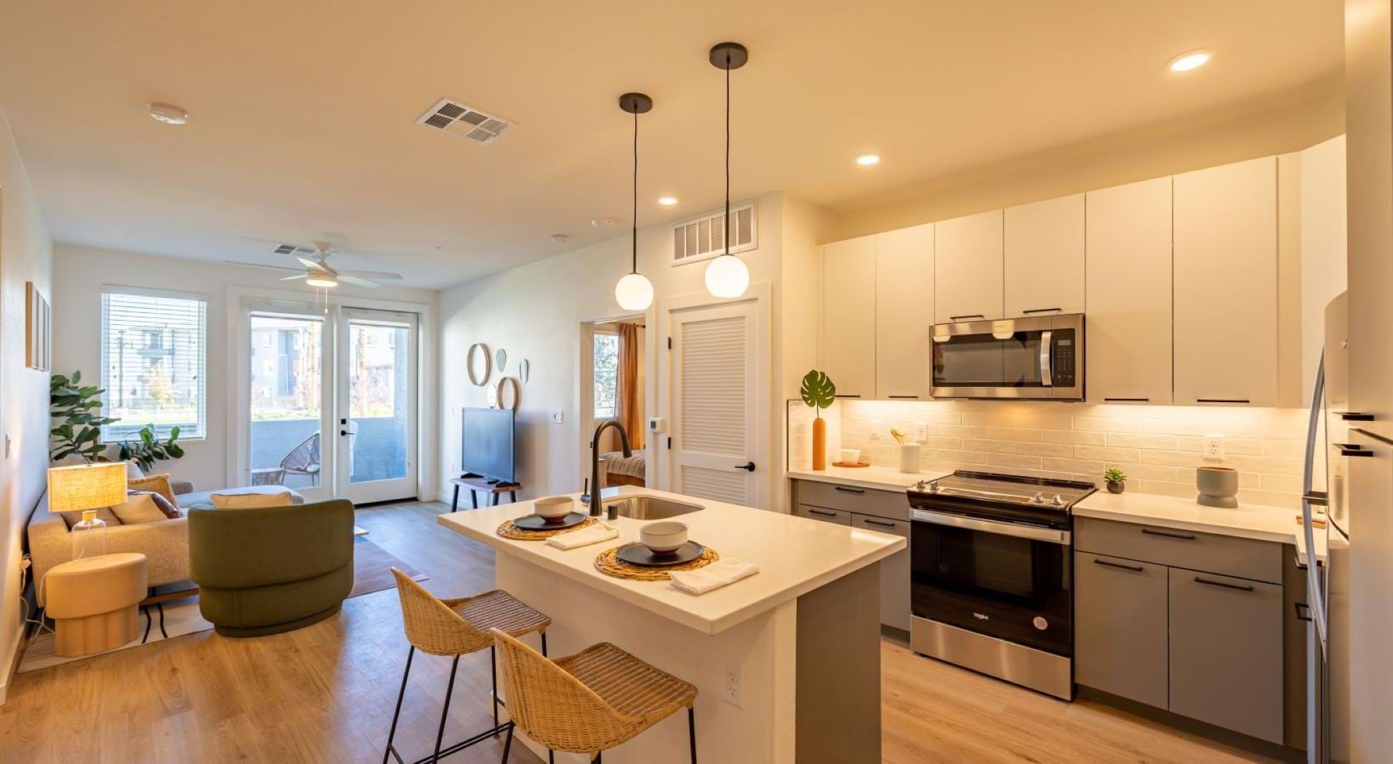 A modern apartment kitchen featuring a center island with barstools, stainless appliances, and living room views.