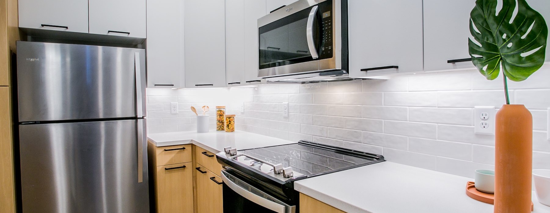 a kitchen with white cabinets and wood floors